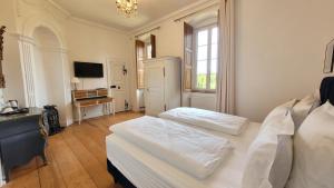 a white bedroom with two beds and a television at Chambres d'Hôtes du Marché aux Grains in Bouxwiller