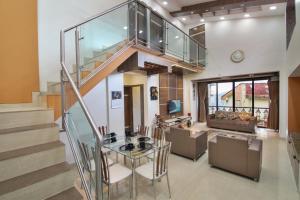 ein Wohnzimmer mit einem Glastisch und einer Treppe in der Unterkunft Titan villa in Panchgani