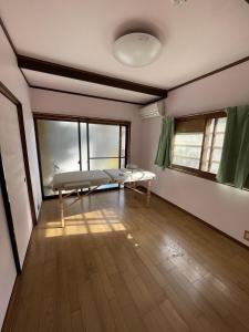 ゲストハウス　鍼灸院　boshcetto في يوشينو: غرفه فيها سرير ونوافذ