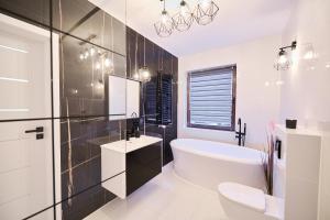 a bathroom with a tub and a sink and a toilet at Villa Agawa in Niechorze