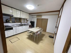 une cuisine avec une table et des chaises. dans l'établissement ゲストハウス　鍼灸院　boshcetto, à Yoshino