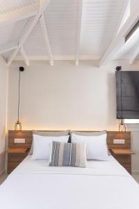 1 dormitorio con 1 cama blanca y TV en la pared en Noemie Premium Holiday Apartments, en Pefkohori