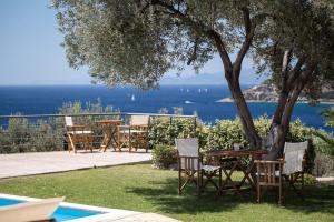 uma mesa e cadeiras debaixo de uma árvore ao lado de uma piscina em Aphaia Villa & Residences Aegina em Agia Marina Aegina