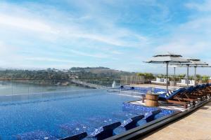 a swimming pool with chairs and an umbrella at Taj Lakefront Bhopal in Bhopal