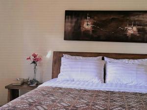 ein Schlafzimmer mit einem Bett mit weißen Kissen und einem Gemälde in der Unterkunft Adi House Homestay in Ubud