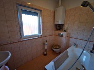 ザマールディにあるVécsey nyaralóházのバスルーム(バスタブ、トイレ付)、窓が備わります。