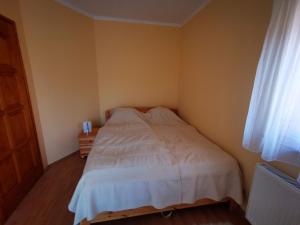 a small bedroom with a white bed and a window at Vécsey nyaralóház in Zamárdi