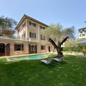 a house with a tree and two chairs in the yard at Resort Al Forte in Forte dei Marmi