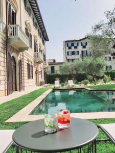 a table with a drink on it next to a swimming pool at Resort Al Forte in Forte dei Marmi