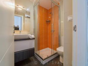 an orange tiled bathroom with a shower and a toilet at Desconectaengalicia Ático La Perla, piscina y pista tenis in Sanxenxo