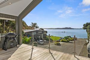 an open deck with a grill and a view of the water at Seaside Serenity - Kerikeri Holiday Home in Kerikeri