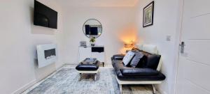 a living room with a black leather couch and a mirror at Criccieth- STUDIO GLAN ERIN BACH in Criccieth