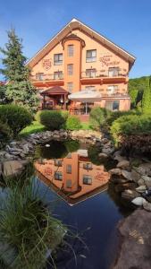 a hotel building with a reflection in a pond at Pensiunea Roua Muntilor in Vadu Crişului