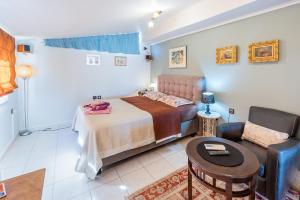 een slaapkamer met een bed, een stoel en een tafel bij Glyfada's Cosy Apartments in Athene