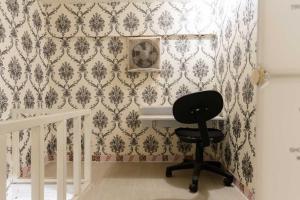uma cadeira preta num quarto com papel de parede em Patent Guest House Syariah RedPartner em Palimbão