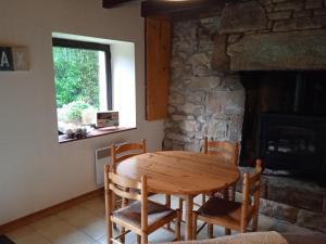 a table and chairs in a room with a stone fireplace at Vacances au calme in Plounevez-Moëdec