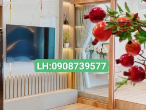 uma sala de estar com televisão e uma planta com fruta vermelha em Căn Hộ TMS 28 Nguyễn Huệ - Xuan Phuong House em Quy Nhon