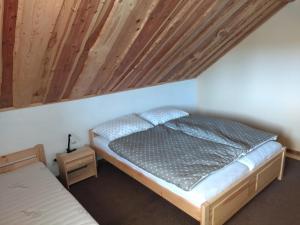 a bed in a room with a wooden ceiling at Apartmán 61 