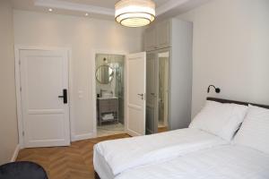 a white bedroom with a bed and a mirror at Apartamenty al Mare Sopot in Sopot