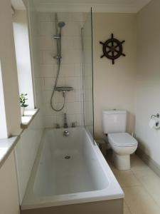 ein Bad mit einer Badewanne und einem WC in der Unterkunft Blakeney Norfolk Bramble Lodge ***Self Catering*** in Blakeney