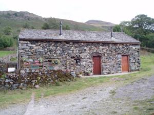 a stone house with red doors and a stone wall at Fisher-gill Camping Barn in Thirlmere