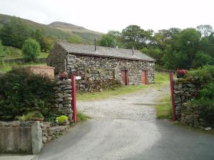 an old stone house with a gate and a dirt road at Fisher-gill Camping Barn in Thirlmere