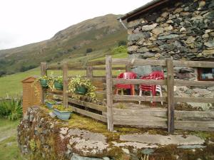 una valla con mesa y sillas frente a un edificio en Fisher-gill Camping Barn, en Thirlmere