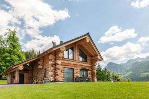 una cabaña de madera en las montañas con césped verde en Das Blockhaus Gosau en Gosau