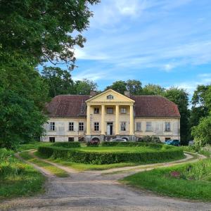 an old house with a road in front of it at Padures muiža in Padure