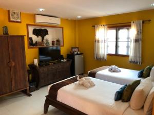 a bedroom with two beds and a flat screen tv at On The Mekong Resort in Luang Prabang