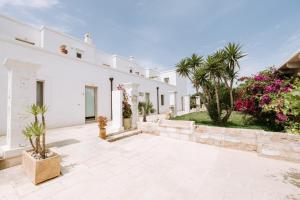 a white house with a courtyard with trees and flowers at Masseria Torrepietra in Monopoli
