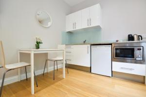 eine Küche mit weißen Schränken und einem Tisch in der Unterkunft Paddington Green Serviced Apartments by Concept Apartments in London