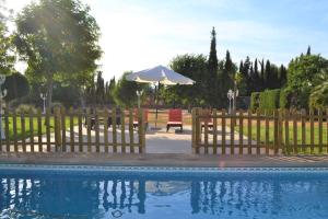 a wooden fence with a pool and an umbrella at Casa Rural Villa Herrera in Fernancaballero