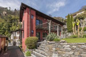 einen Blick auf ein rotes Haus mit einer Steinmauer in der Unterkunft Casa Moscia in Ascona