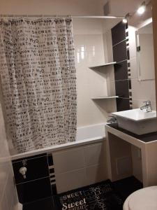 łazienka z zasłoną prysznicową i umywalką w obiekcie Sunnyrise Apartman w mieście Hódmezővásárhely +13 zdjęć