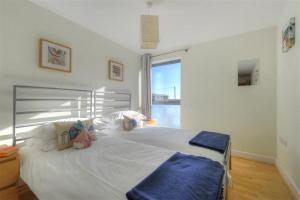 een slaapkamer met een groot wit bed en een raam bij 8 Driftwood in West Bay