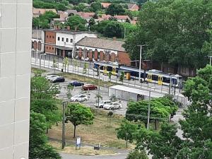 pociąg jadący ulicą obok parkingu w obiekcie Sunnyrise Apartman w mieście Hódmezővásárhely