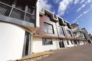 a building with a row of windows on a street at 8 Driftwood in West Bay