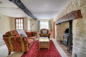 a living room with two couches and a stone fireplace at Smugglers Cottage in Beer
