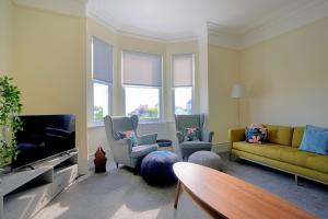 a living room with a couch and chairs and a tv at 7 Seafield Road in Seaton