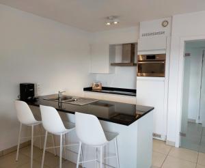 a kitchen with white cabinets and a black counter top at Duplex Villa Capricia appartement met zwembad Nieuwpoort Jachthaven in Nieuwpoort