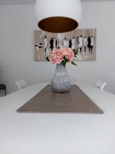 a vase with pink flowers sitting on a table at Duplex Villa Capricia appartement met zwembad Nieuwpoort Jachthaven in Nieuwpoort