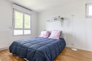 een slaapkamer met een groot blauw bed met 2 roze kussens bij Design 3 bedrooms appartment, near Champs Elysees in Nanterre