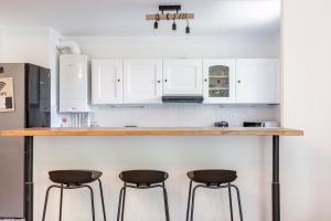 a kitchen with white cabinets and bar stools at Design 3 bedrooms appartment, near Champs Elysees in Nanterre
