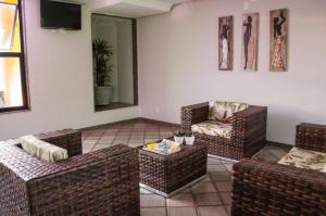 sala de estar con muebles de mimbre y TV en Hotel Portal Premium, en Brumado