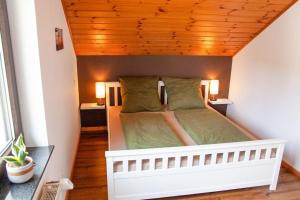 a bedroom with a white bed with a wooden ceiling at Eifelruh in Hellenthal