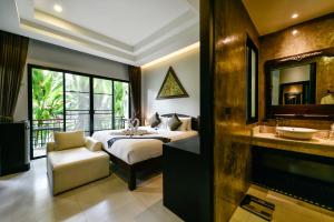 a bedroom with a bed and a bathroom with a sink at Coco Paradiso Phuket SHA in Phuket Town