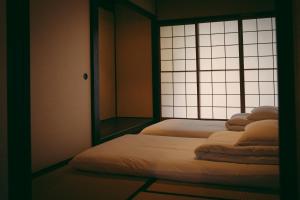 twee bedden in een kamer met een raam bij Kotone Machiya-Inn 京町家旅宿 小都音 in Kyoto