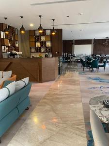 een lobby met een bank en tafels en een restaurant bij Rosa Grand Hotel in Riyad