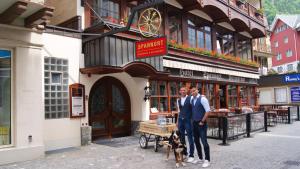 zwei Männer stehen vor einem Gebäude mit einem Hund in der Unterkunft Family-Hostel SPANNORT with common kitchen and self check-in in Engelberg